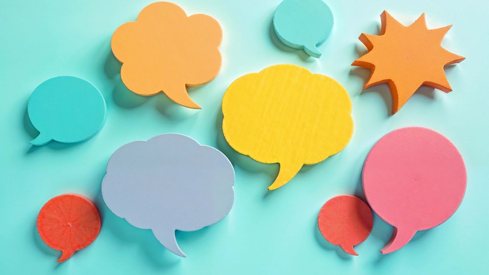 Colourful paper cut-out speech bubbles scattered on a turquoise background